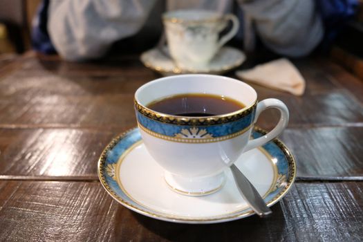 Spoon and cup of coffee on wooden table