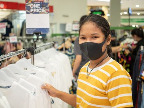 A woman wearing a protective mask While choosing a product In the mall.