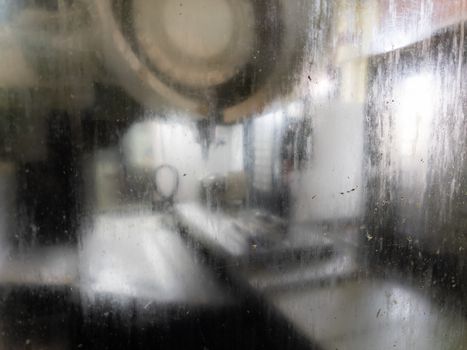 wet and dirty protective glass of cnc milling machine - close-up with selective focus and blur