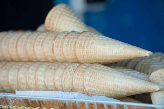 A lot of empty ice cream cones are on the stand. Cooking ice cream on the street