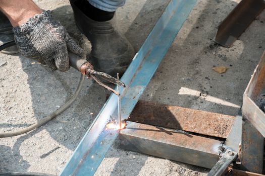 Welder welds metal structure. Construction worker at work. A working welder builds or repairs a new porch and facade of a building or structure. Construction and repair work on the street outdoor.