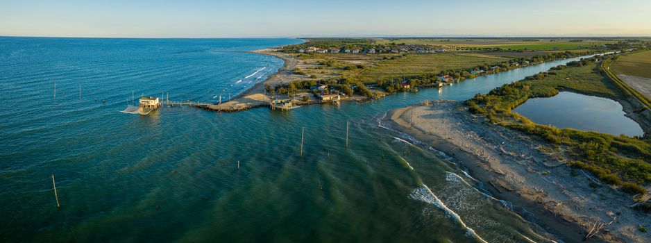 beautiful panorama of the valleys near Ravenna (Fiumi Uniti) where the river flows into the sea with the typical fishermen's huts at sunset