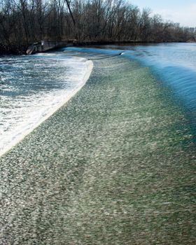 Fast Flowing Water Crashing Over a Man-Made Dam in a Dead Winter Forest