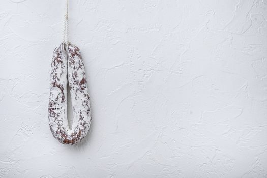 Salami sausage fuet on white textured background with copy space.