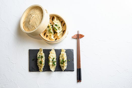 steamed dumpling or Japanese gyoza, dumplings snack in traditional wooden steamer and black stone slate on white texture stone background top view space for text