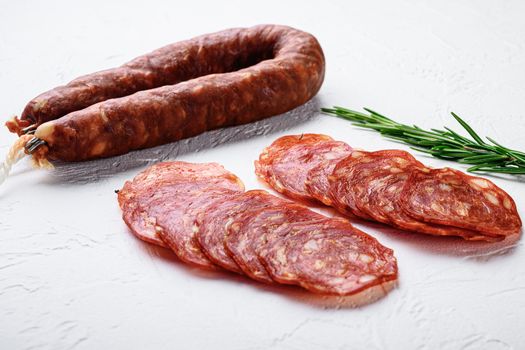 Sliced cuts of chorizo salami sausage on white surface.