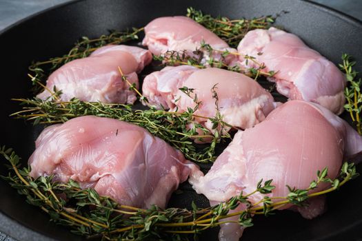 Chicken thighs on iron cast on grey background.
