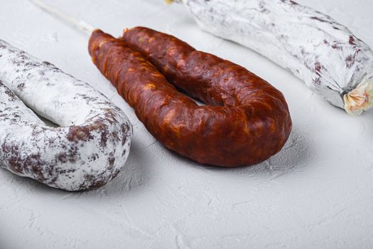 Chorizo and fuet salami on white textured background.