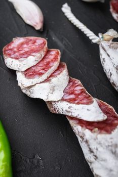 Dry cured fuet salami sausage slices on balck background.