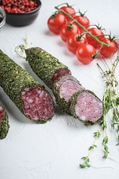 Traditianal fuet sausage in herbs with ingredients on white surface.