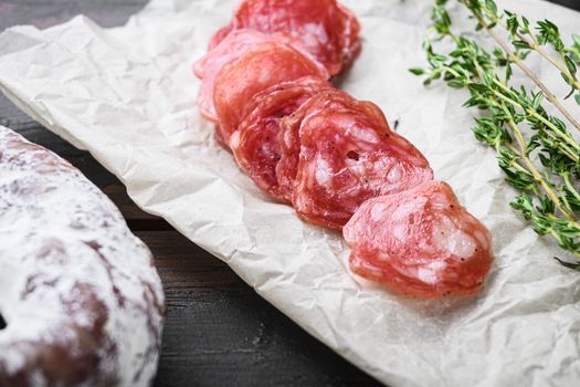Fuet, dry cured sausage cut to slices on old wooden table.