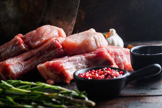 Bio Pork Chops from organic farm with spices: pepper, salt, bay leaf. Butcher chopping cleaver in wood table over rustic wood and metal Food background side view selective focus close up.