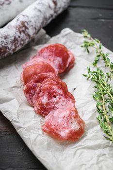 Fuet, dry cured sausage cut to slices on old wooden table.