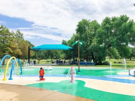 Colorful splash park with shaded picnic areas near Dallas, Texas, America. Recreation site with splashing water fountains for kids summertime activities