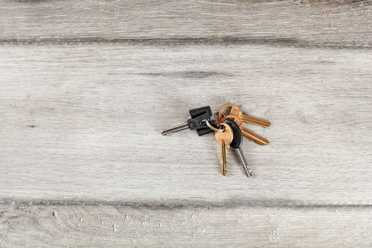 Keys on keyring dropped on laminate gray wood floor.