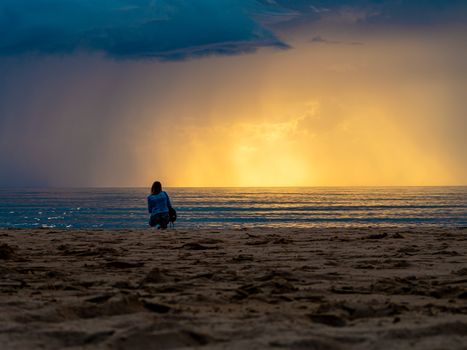 beautiful alone girl on the beach. Girl looking at stormy sea amd taking a picture with smarphone. The spectacular Storm with rain Is Coming in Estonia. Baltic sea