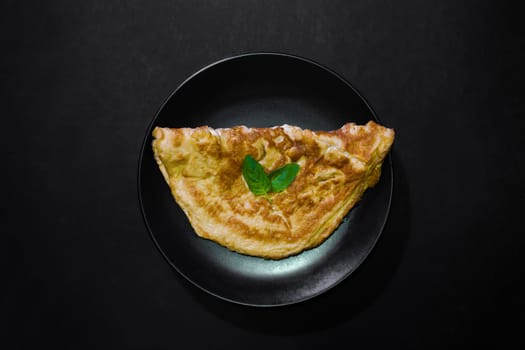 Picture of an appetizing yellow omelette on a black background There is space to put text. Street food, Image from the top view