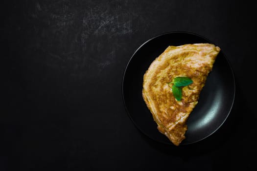 Picture of an appetizing yellow omelette on a black background There is space to put text. Street food, Image from the top view