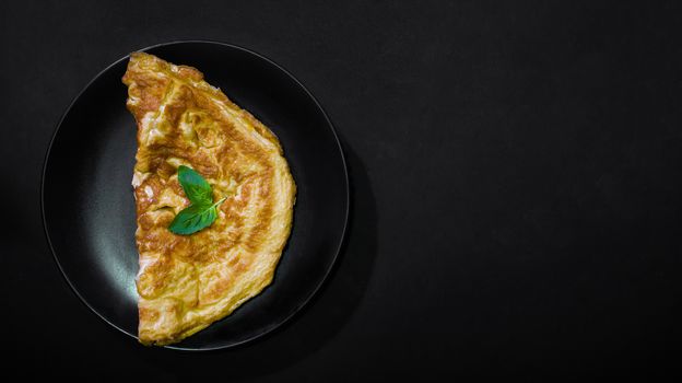 Picture of an appetizing yellow omelette on a black background There is space to put text. Street food, Image from the top view