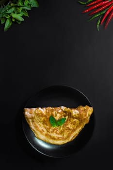 Picture of an appetizing yellow omelette on a black background There is space to put text. Street food, Image from the top view