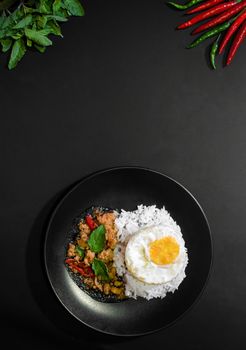 Rice with pork stir fried with basil and fried egg on black background, Thai food, Street food, Image from the top view