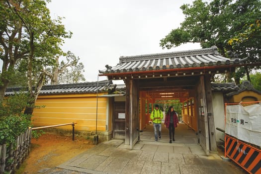 Kyoto, Japan - December 17, 2019 : Tourists walking through the entrance gate of Kinkakuji temple, Kyoto, Japan.