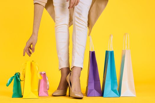 female feet in shoes packs shopping lifestyle yellow isolated background. High quality photo