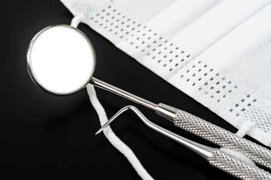 Set of metal Dentist's medical equipment tools on black backgound.