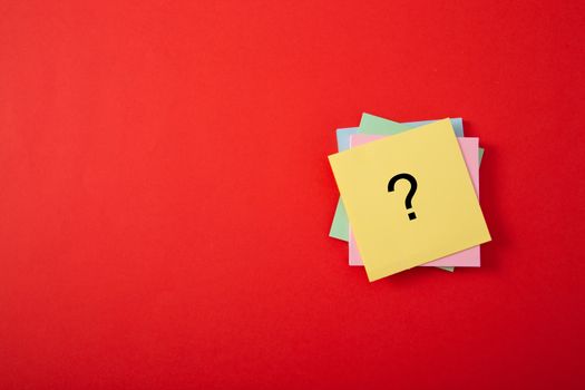 Question mark drawn on notepad. Over red background with copy space.