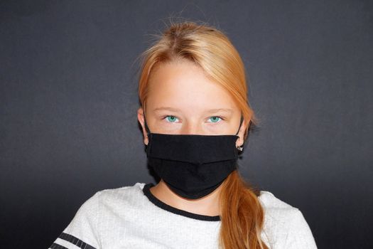 teenage girl in a black medical mask on a black background, portrait