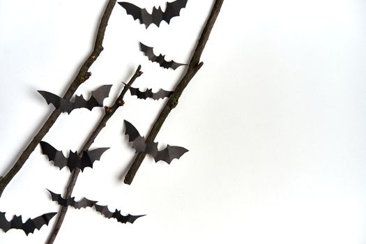 Halloween decoration concept black paper bats dry branch stick white cardboard background With copy space for tetxt