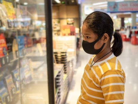 Long haired girl Wear a protective mask Looking at the showcase In a bookstore. Concept of life And protect yourself from the coronavirus outbreak.