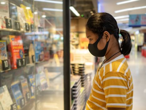 Long haired girl Wear a protective mask Looking at the showcase In a bookstore. Concept of life And protect yourself from the coronavirus outbreak.