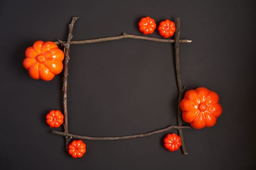 Halloween background, orange decorative plastic pumpkin black paper dry branch stick square frame black cardboard Thanksgiving greeting card pattern
