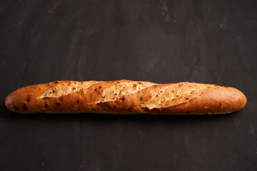 one crispy french baguettes lie dark black table background sesame seeds Classic french national pastries Copy space Concept for menu or advertising