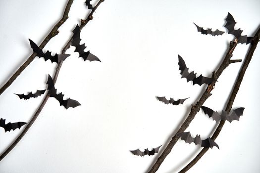 Halloween decoration concept black paper bats dry branch stick white cardboard background With copy space for tetxt