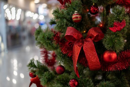 Close Christmas tree in a shopping center against the background of blurry shop windows. Free space for text