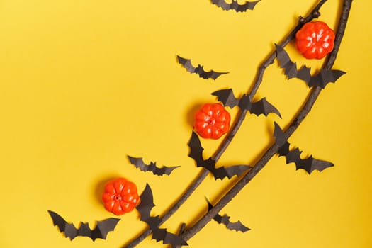 Halloween background, orange decorative plastic pumpkin black paper bat dry branch stick yellow cardboard Thanksgiving greeting card pattern