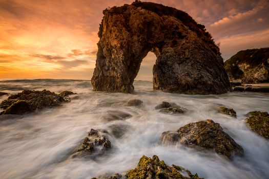 Choppy sea with fast tidal flow and a magnificent sunrise at Horsehead Rock Australia.  Travel destination natural formation rock eroded into shape of horse drinking water