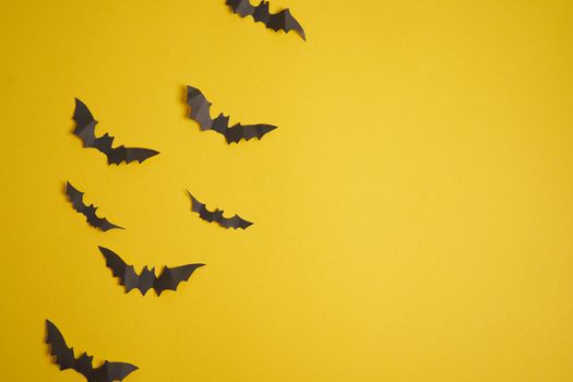 Halloween decoration concept black paper bats yellow cardboard background With copy space for tetxt