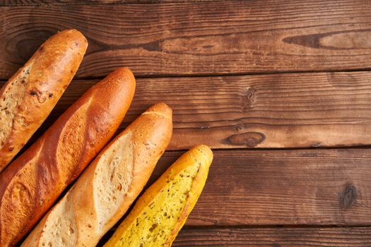 Three crispy french baguettes lie on an old wooden table with free space for text baguettes in assortment with sesame seeds Classic french national pastries Copy space Concept for menu or advertising