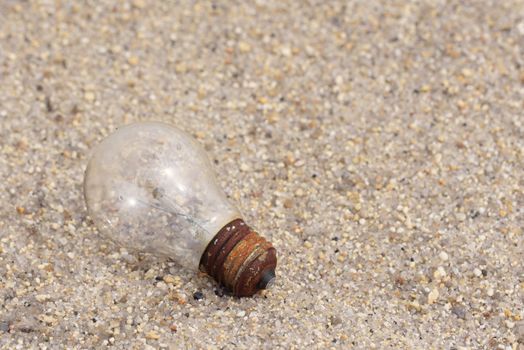 Electric light bulb on sand. Old light bulb on the floor