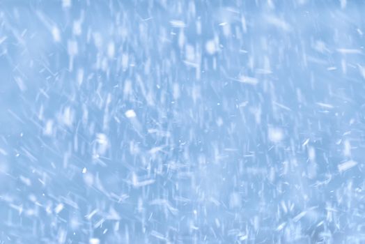 Falling snow on a blue background. Winter blue sky with falling snow