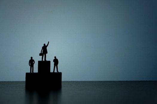 Business strategy conceptual photo - Silhouette of miniature businessman standing on podium while pointing upside