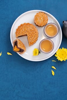 Moon cake for Mid-Autumn Festival, delicious beautiful fresh mooncake on a plate over blue background table, top view, flat lay layout design concept.