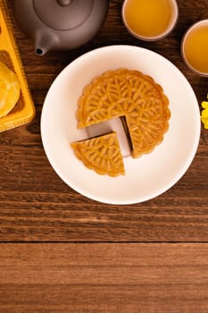 Moon cake for Mid-Autumn Festival, delicious beautiful fresh mooncake on a plate over dark wooden background table, top view, flat lay layout design concept.