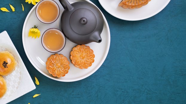 Moon cake for Mid-Autumn Festival, delicious beautiful fresh mooncake on a plate over blue background table, top view, flat lay layout design concept.