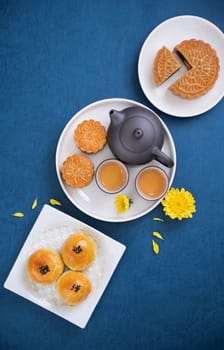 Moon cake for Mid-Autumn Festival, delicious beautiful fresh mooncake on a plate over blue background table, top view, flat lay layout design concept.