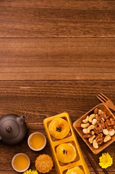 Moon cake for Mid-Autumn Festival, delicious beautiful fresh mooncake on a plate over dark wooden background table, top view, flat lay layout design concept.