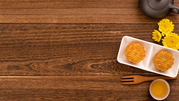 Moon cake for Mid-Autumn Festival, delicious beautiful fresh mooncake on a plate over dark wooden background table, top view, flat lay layout design concept.